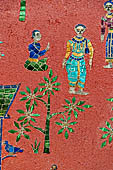 Wat Xieng Thong temple in Luang Prabang, Laos.  La Chapelle Rouge , the Red Chapel. The exterior walls are decorated with colourful mosaics on a pink background with scenes of people daily activities. North wall.